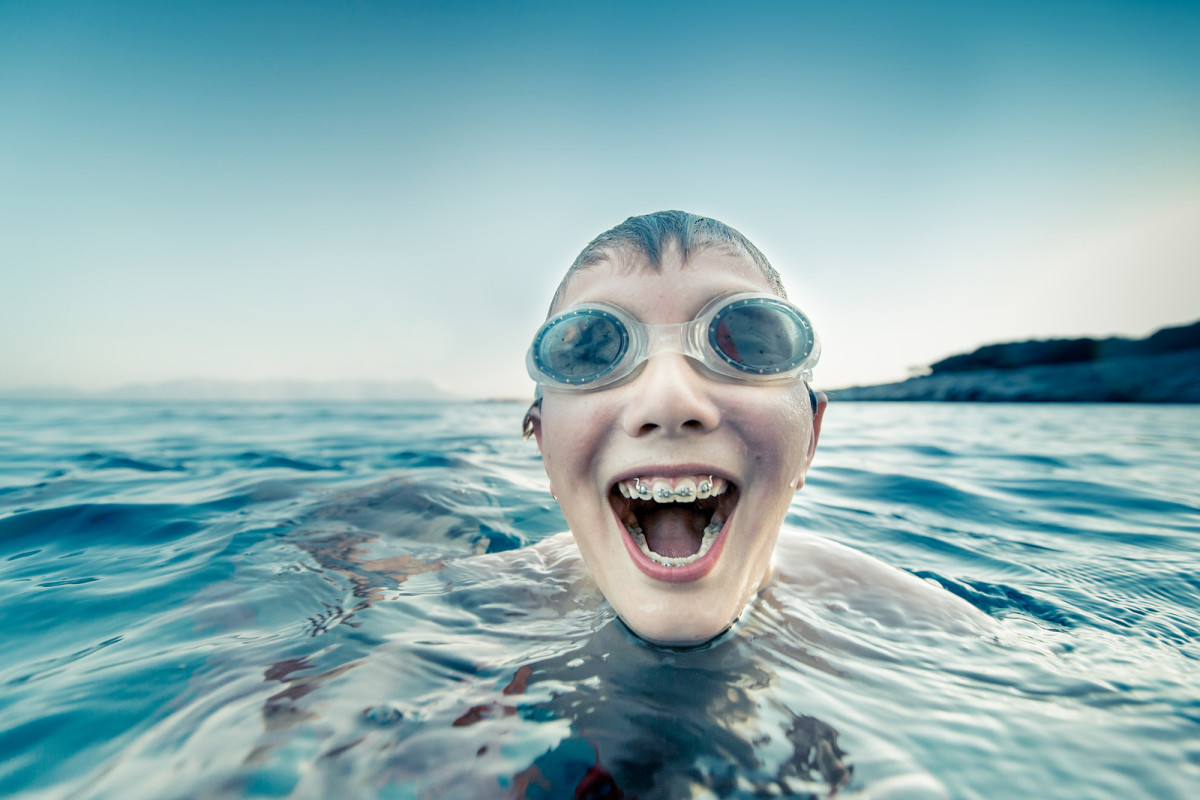 Boy with braces swimming and laughing