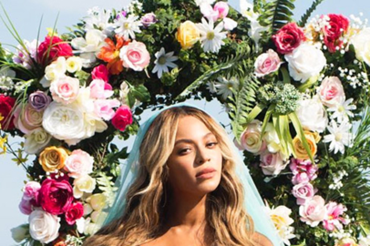 Beyonce with blue veil posing with her new twins in front of flowers