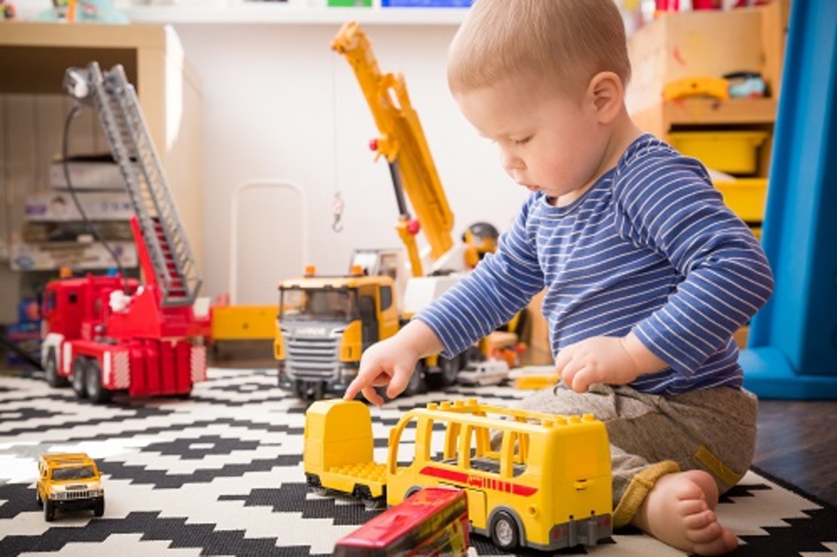 Cute little baby boy playing with toy school bus in his room. Indoors activities with children. Child playing in kid's room.